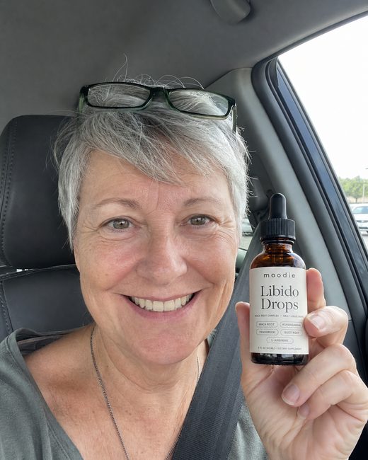 Moodie customer, 61, car, holding her bottle of Libido Drops