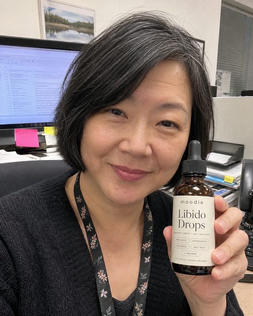 Moodie customer, 55, office, holding her bottle of Libido Drops