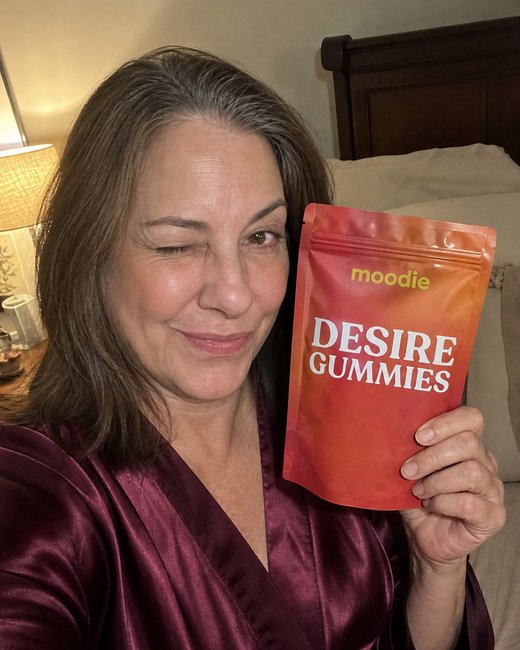 Moodie customer, 52, bedroom, holding her pouch of Desire Gummies