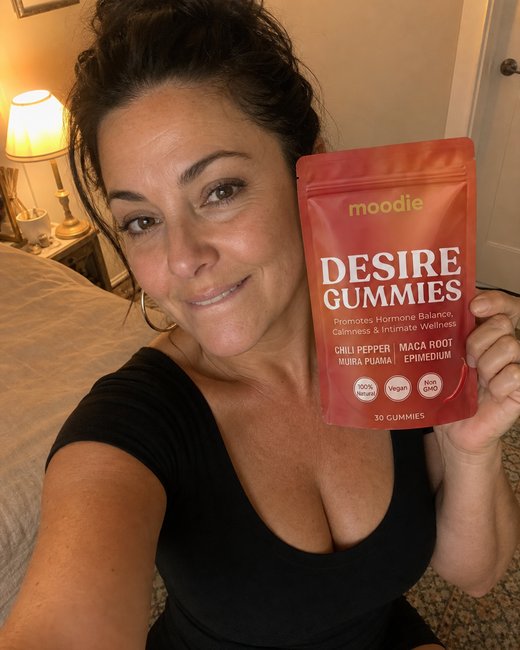 Moodie customer, 47, bathroom mirror, holding her pouch of Desire Gummies